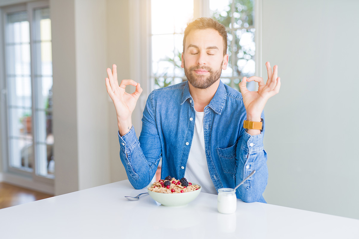 calm, happy man sits to eat a bowl of oatmeal with fruit